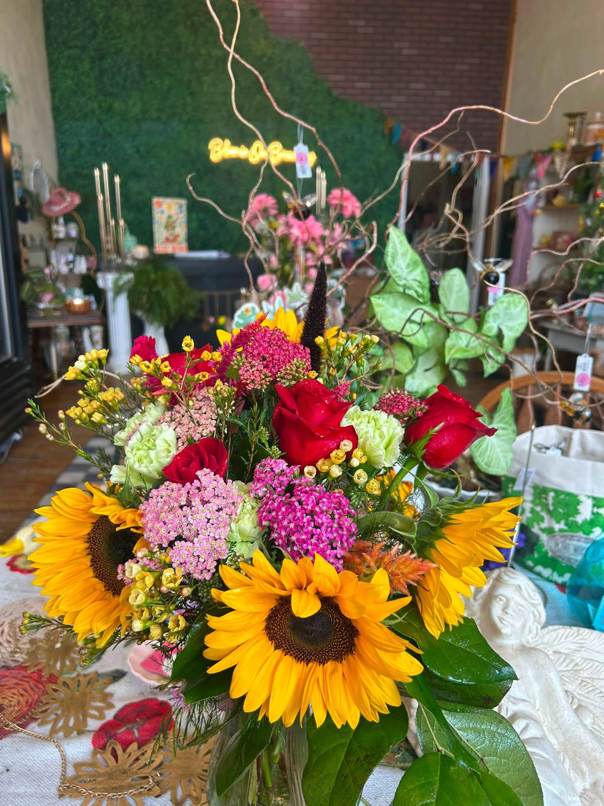 A bright bouquet of sunflowers, red roses and pink yarrow